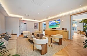 A modern hotel lobby with a reception desk, seating area, and a large TV screen. - Sky Studio 34 | Rooftop Pool & Panoramic Views (Miami)