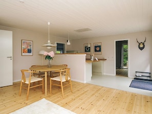 A modern interior with a wooden dining table, chairs, a vase of flowers, pendant lights, and a deer skull on the wall. - 4 Star Holiday Home in Gilleleje (Gilleleje)
