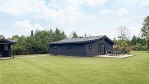 A single-story building with a flat roof, a door, and a small porch with a table and chairs. - 4 Star Holiday Home in Gilleleje (Gilleleje)