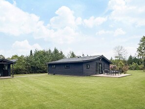 A single-story building with a flat roof, a door, and a small porch with a table and chairs. - 4 Star Holiday Home in Gilleleje (Gilleleje)