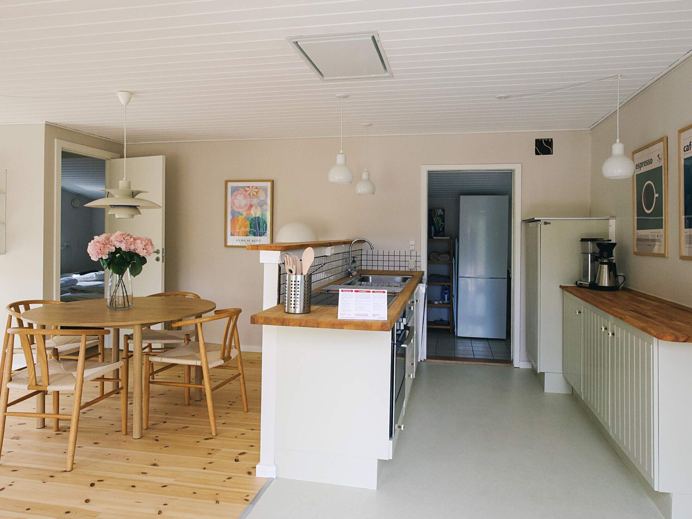 Une cuisine moderne avec un plancher en bois, un îlot central et des luminaires suspendus.