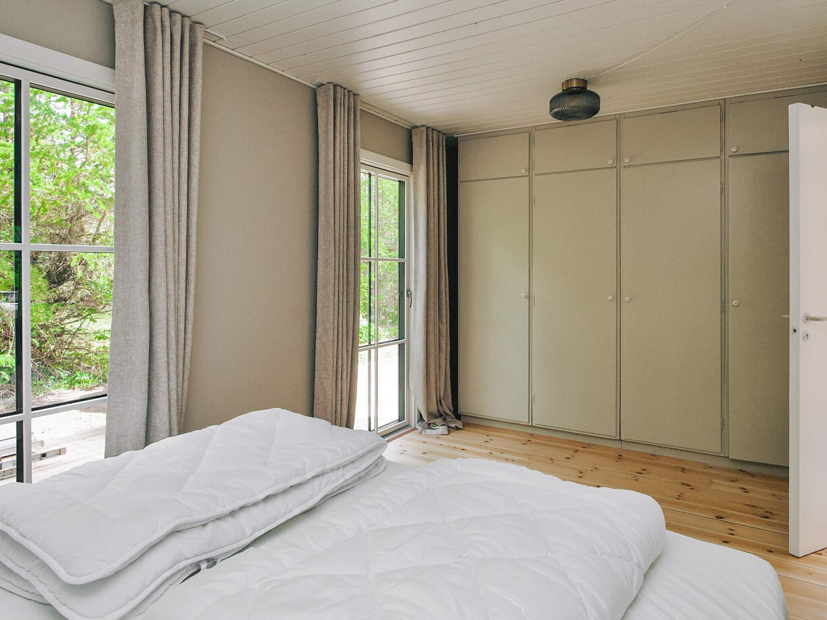 A bedroom with a bed, a wardrobe, and a window with curtains.