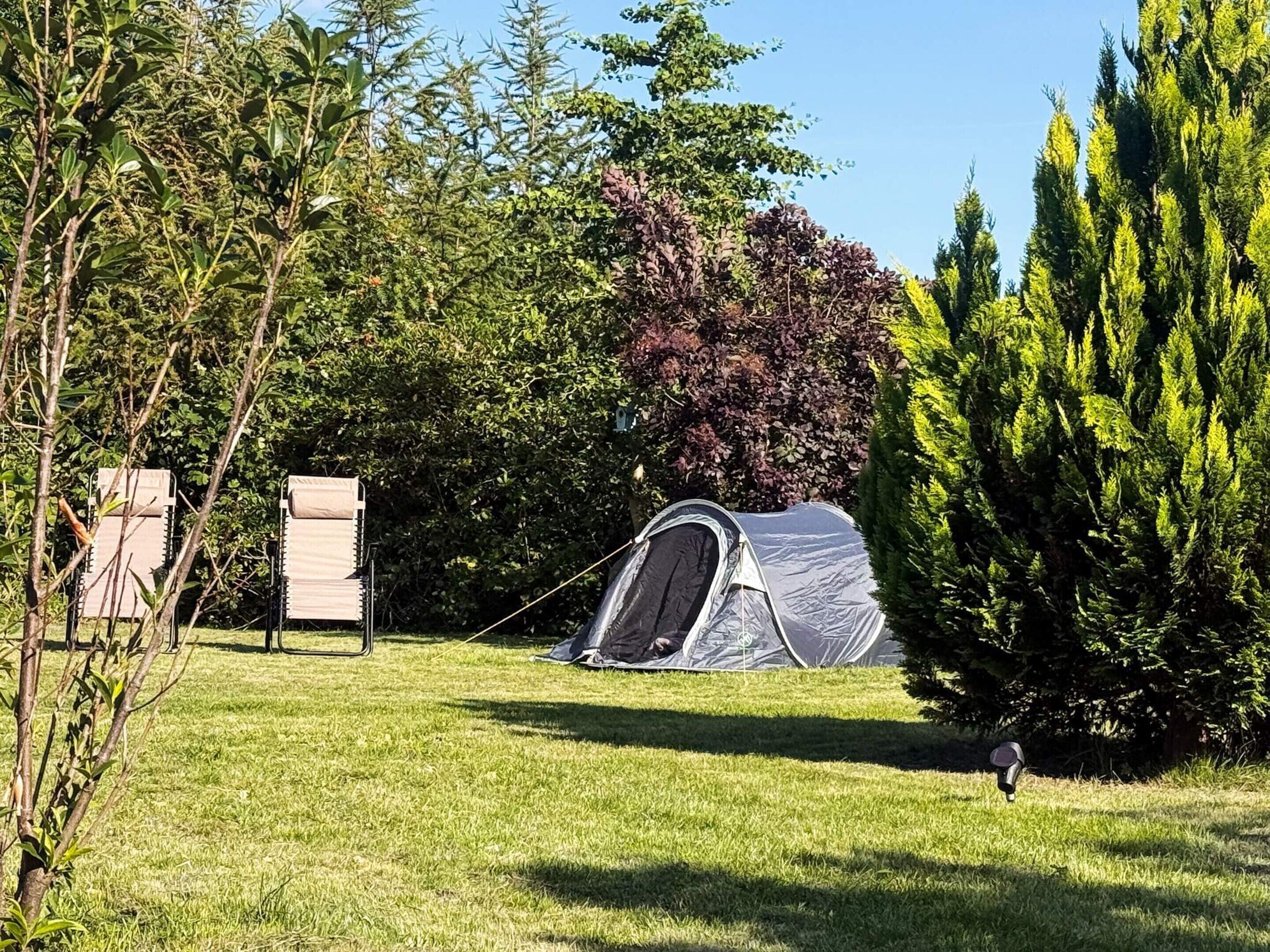 Ein Campingplatz mit Zelt, einer mobilen Toilette und einem Rasenfeld.