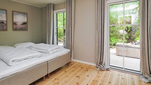 A bedroom with a bed, wooden flooring, a window, and a view of greenery outside. - 4 Star Holiday Home in Gilleleje (Gilleleje)