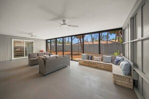 A spacious patio with a ceiling fan, a built-in bench, and a view of the backyard. - The Sea Salt Grand Suite: Modern Siesta Charm (Siesta Key)
