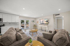 A modern living room with a sofa set, a coffee table, and a TV. - The Sea Salt Grand Suite: Modern Siesta Charm (Siesta Key)