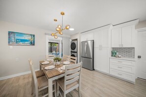 Eine moderne Küche mit weißen Schränken, Edelstahlgeräten und einem Essbereich mit Holztisch und Stühlen.