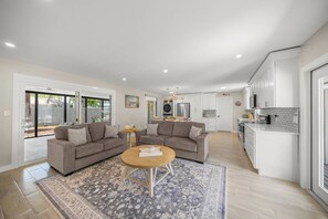 Ein großzügiges Wohnzimmer mit einer großen Sofagarnitur, einem runden Couchtisch und einem gemusterten Teppich.