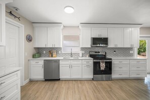 A modern kitchen with white cabinets, a stainless steel dishwasher, and a built-in oven. - The Sea Salt Grand Suite: Modern Siesta Charm (Siesta Key)