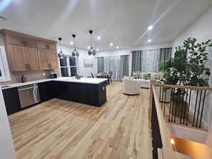 A modern kitchen with wooden cabinets, a central island, and pendant lighting.