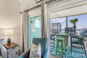 Une chambre d’hôtel avec balcon, vue sur la plage et coin repas aménagé avec du mobilier d’extérieur.