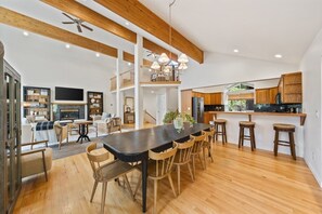 Una cocina amplia con vigas de madera, un comedor con una mesa larga y una sala de estar con chimenea.