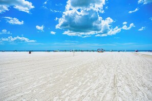 Ein weiter Sandstrand mit blauem Himmel und ferner Küste.