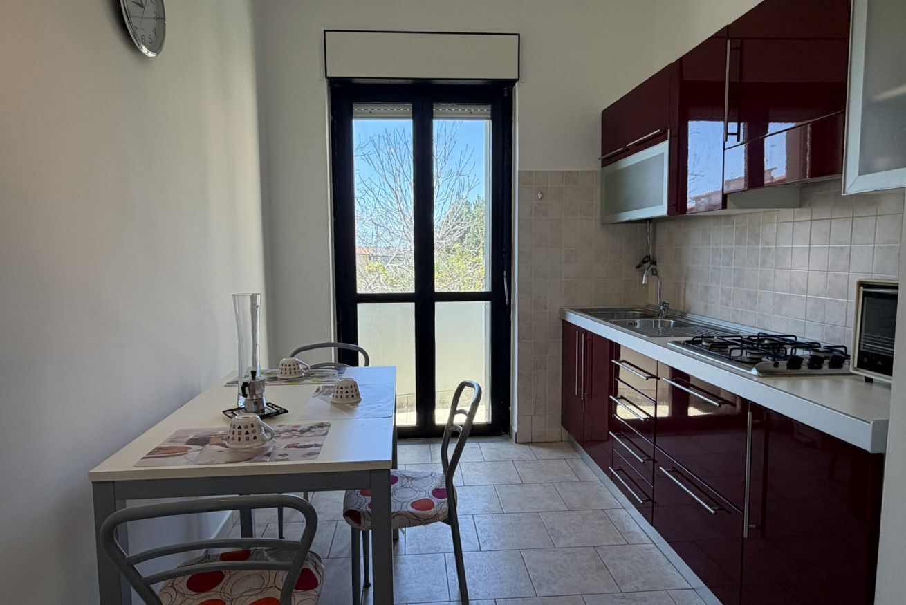 Una cucina con tavolo e sedie, fornello, mobili e una finestra.