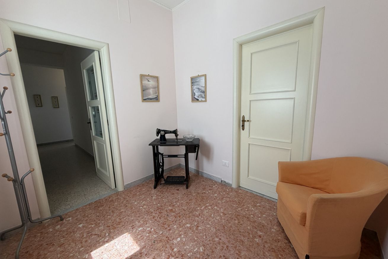 Una stanza con una macchina da cucire, una sedia e una porta.