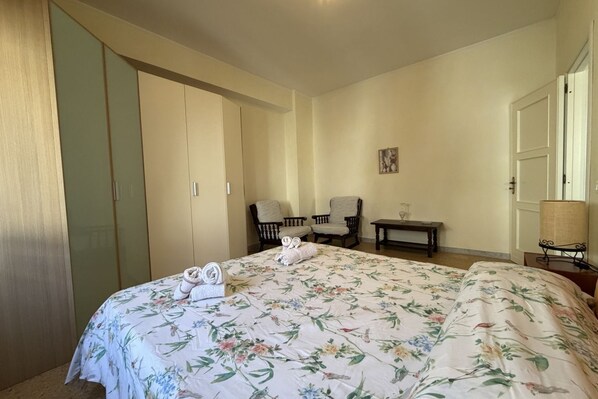 Une chambre à coucher avec un lit, deux chaises, une petite table et une armoire.
