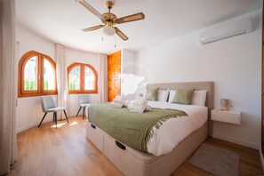 Ein Schlafzimmer mit einem Bett, zwei Stühlen, einem Deckenventilator und einem Nachttisch.