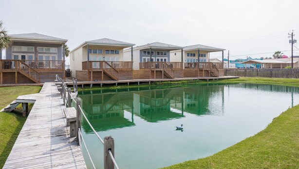 Eine Reihe von Ferienhäusern am Wasser mit Holzdecks und ruhiger Wasserfläche.