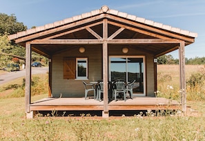 A wooden cabin with a covered porch, a sliding glass door, and a number '24' sign.