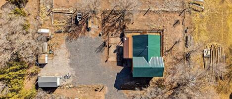 An aerial view of a property with a green-roofed building, a fenced area, and scattered structures.