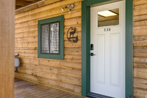 A log cabin with a white door marked '538,' a checkered window, and a deer logo on the wall.