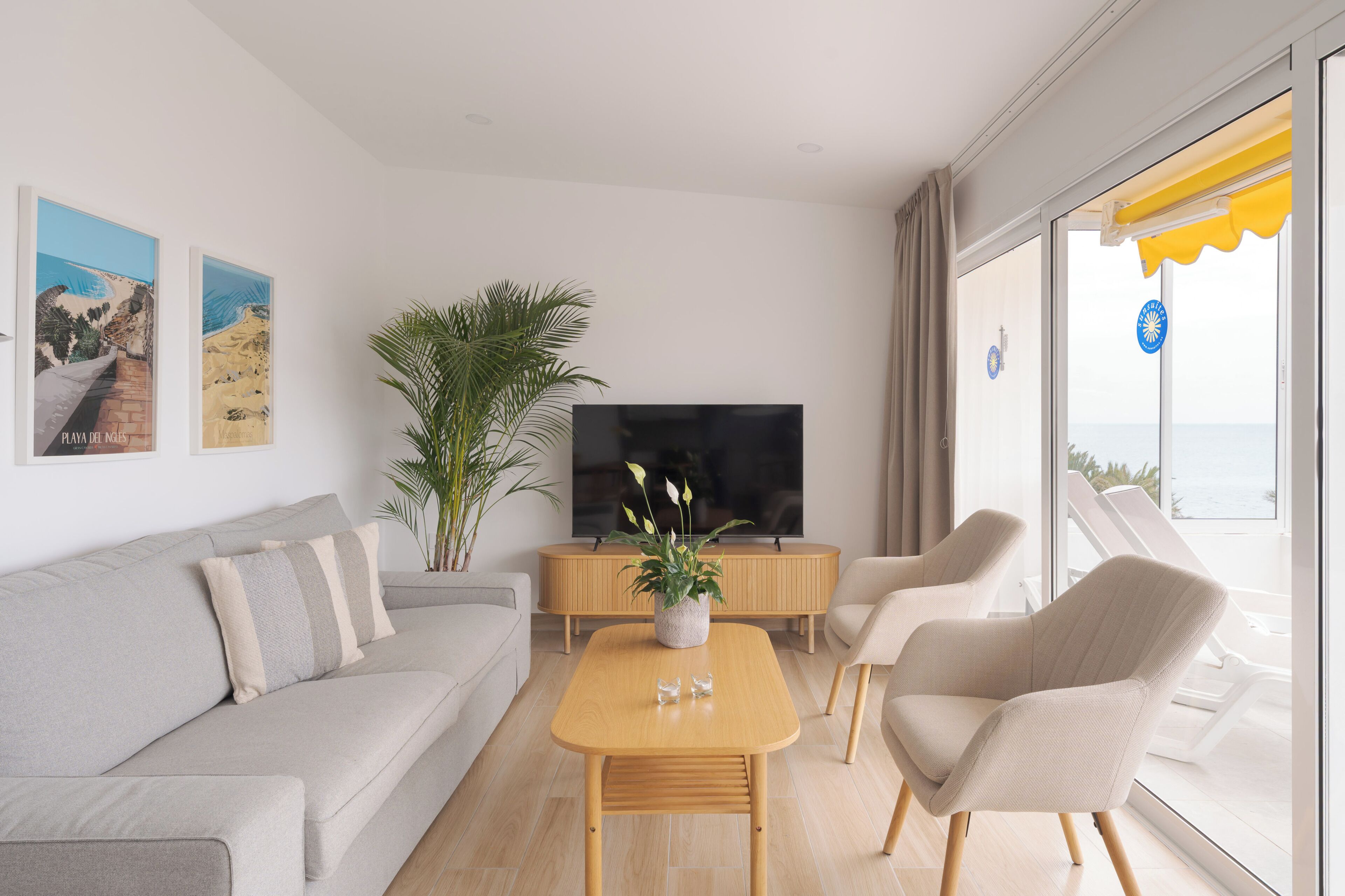 Una sala de estar moderna con un sofá, una mesa de centro, un televisor y un ventanal con vistas.