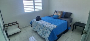 Ein Schlafzimmer mit einem Bett, einem kleinen Tisch, einem Stuhl und einem Fenster.