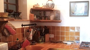 Cozinha com pia, fogão e diversos utensílios e recipientes nas prateleiras.