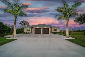 A two-story house with a garage, surrounded by a well-maintained lawn and palm trees. - Sleeps 6, full refund*, shared heated salt pool (Rotonda West)