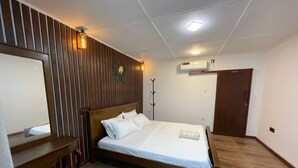 A bedroom with a wooden bed, a bedside table, a mirror, a wall-mounted heater, and an air conditioning unit.