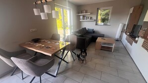 Uma sala de estar moderna com mesa de jantar, sofá e aparador para TV.