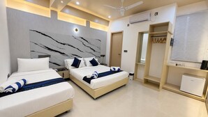A modern hotel room with two beds, a wardrobe, a desk, and a small kitchenette. - Ocean Bounty (Ukulhas)