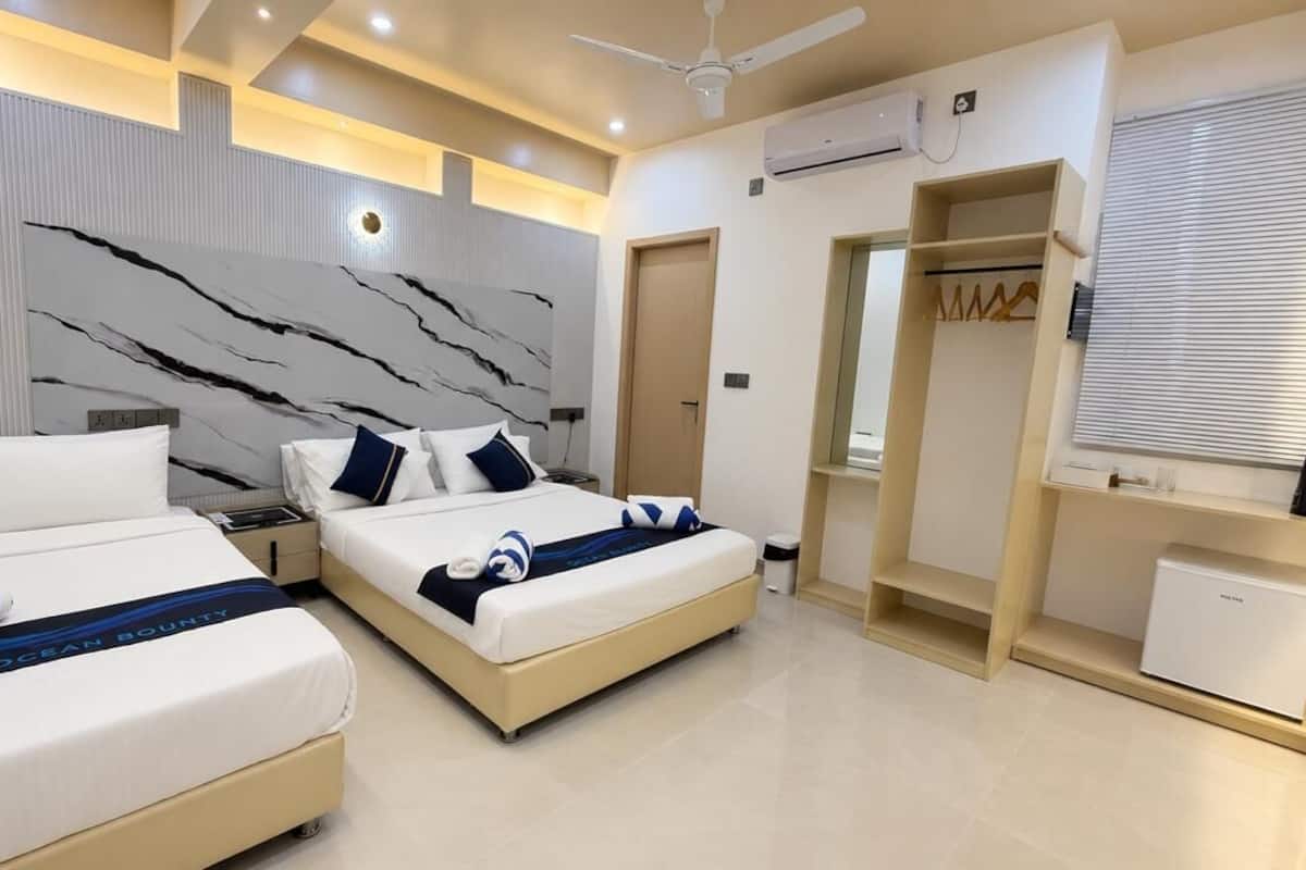 Une chambre d’hôtel moderne équipée de deux lits, d’une armoire, d’un bureau et d’une petite kitchenette.