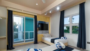 A modern hotel room with a large sliding glass door to the balcony, a bed with a blue and white striped blanket, and a flat-screen TV mounted on the wall. - Ocean Bounty (Ukulhas)
