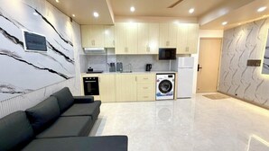 A modern kitchen with built-in appliances, a washing machine, and a dining area with a sofa. - Ocean Bounty (Ukulhas)