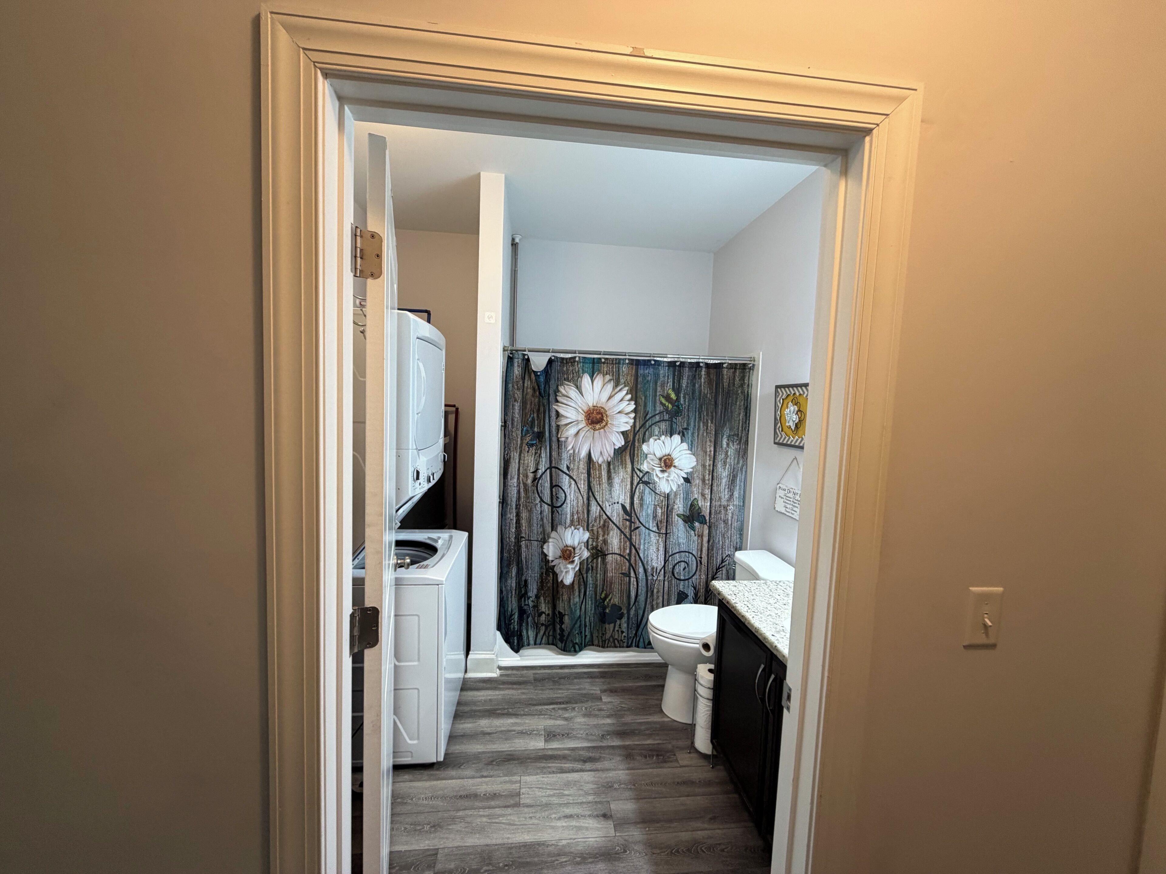 Un baño con cortina de ducha, inodoro y lavadora.