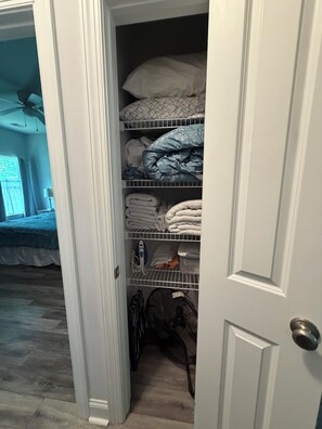 Un dormitorio con cama, armario con estantes y ventana.