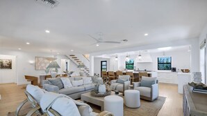Un vaste espace de vie comprenant un canapé, des fauteuils, une table basse et un escalier menant à l’étage supérieur.