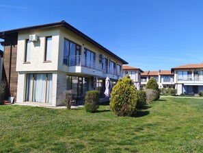 A two-story residential building with balconies, a lawn, and a clear blue sky. - Charming 3-bedroom house in gorgeous Balchik with AC and gym (Balchik)
