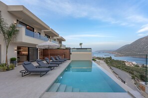 Ein modernes Gebäude mit Pool, Liegestühlen und Blick auf das Meer.