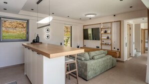 Una cucina moderna con un piano di lavoro in legno, un'area salotto integrata e un'ampia finestra.