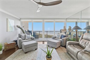 Ein geräumiger Wohnbereich mit großem Fenster, Deckenventilator und Blick ins Freie.