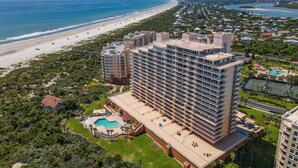 Ein Hochhaus-Hotel mit zahlreichen Balkonen mit Blick auf einen Strand und ein Schwimmbecken.
