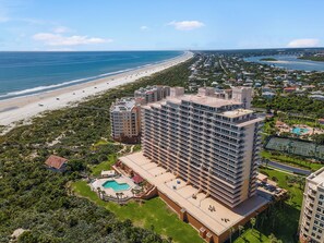 Ein Hochhaus-Hotel mit mehreren Etagen, einem Schwimmbad und Blick auf den Strand.