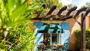 A patio with a table and chairs, a green umbrella, and a wooden pergola. - Charming Countryside Maisonette (Les Mathes)