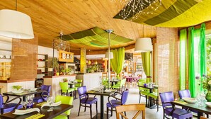 A restaurant with wooden ceiling, green and purple chairs, and a bar area. - Charming Countryside Maisonette (Les Mathes)