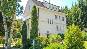Un edificio de varios pisos con un jardín delantero, rodeado de árboles.
