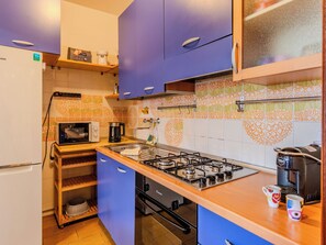Une cuisine compacte équipée d’une cuisinière à gaz, d’un four à micro-ondes et d’une machine à café.