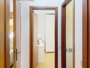 A hallway with a wooden door frame, a white door, and a tiled wall. - Casa Elena by Interhome (Bellano)