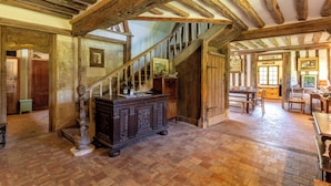 A rustic interior with exposed wooden beams, a staircase, and a brick floor. - La Bécassière | Family Normandy house with pool & nature (Genneville)